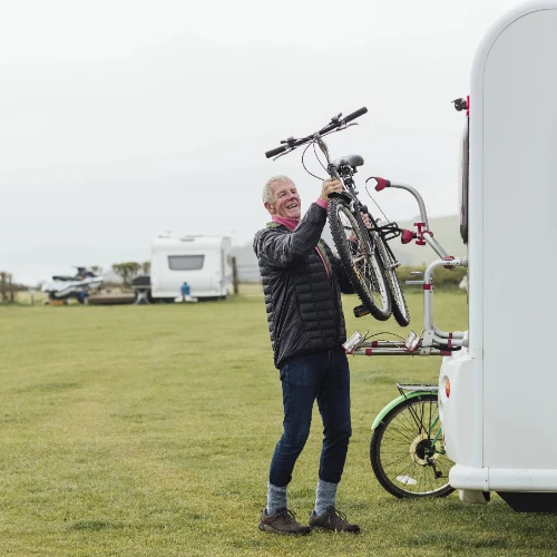 a cyclist putting their bike on the back of their caravan