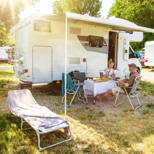 Couple sitting outside at table next to motorhome