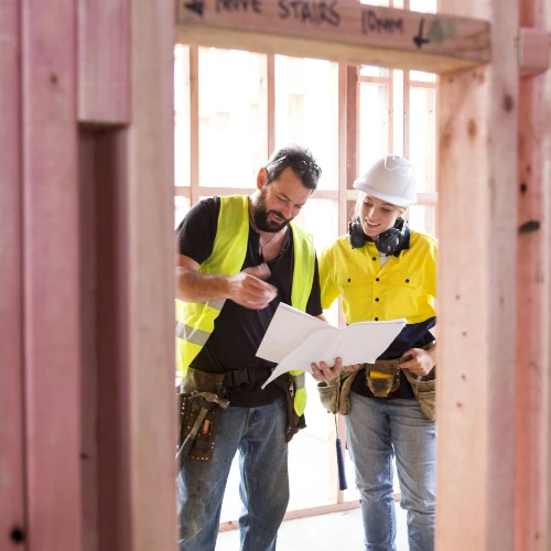 Two contractors examining papers inside a house