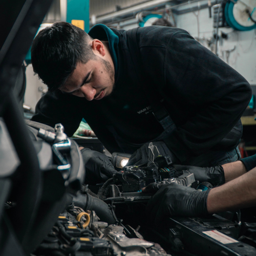 Two mechanics placing car parts into vehicle
