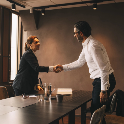 Woman lawyer and man shake hands over conference table