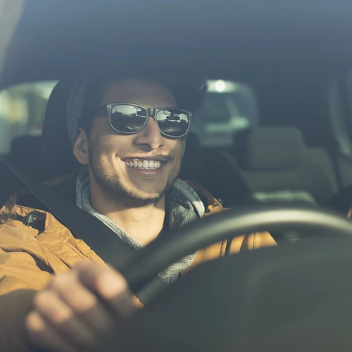 Man smiling at wheel of car