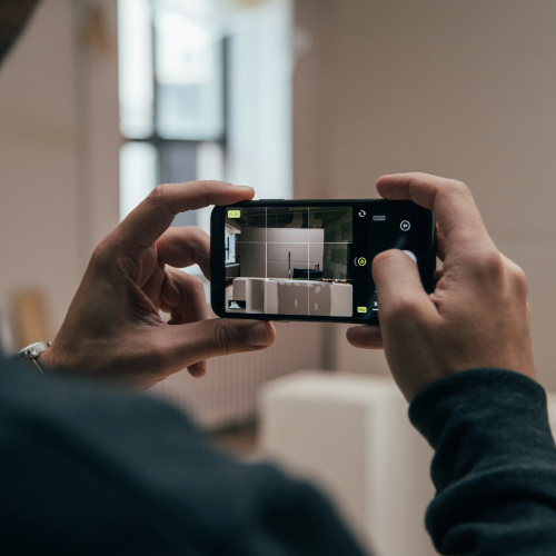 man taking photo of house on phone