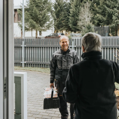 Man smiling at woman in doorway with toolkit