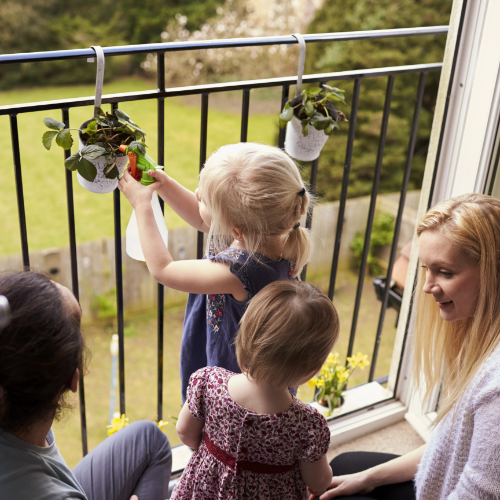 Two mothers with children on apartment balcony