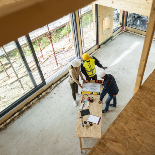 Three construction workers discussing plans on table