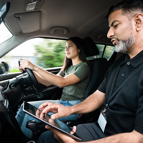A driving instructor teaching a student whilst on the road and in the passenger seat